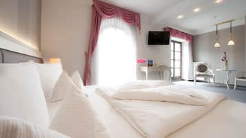 Una habitación de hotel con una cama grande, un escritorio, una silla, un televisor y una ventana con cortinas.