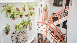 A multi-level interior with potted plants on the walls, a spiral staircase with orange railings, and a patterned floor design. - Hotel La Casona (Iquitos)