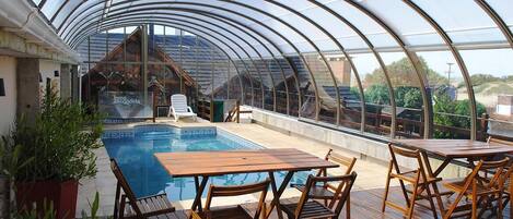 Piscine couverte, piscine extérieure, parasols de plage, chaises longues