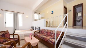 Un vaste espace de vie comprenant un canapé, des fauteuils, une petite table et un escalier menant à l’étage supérieur.