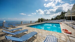 Un espace piscine avec des chaises longues et vue sur la mer.