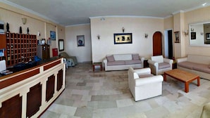 Un salon comprenant un canapé, des fauteuils, une table basse et un comptoir d’accueil.
