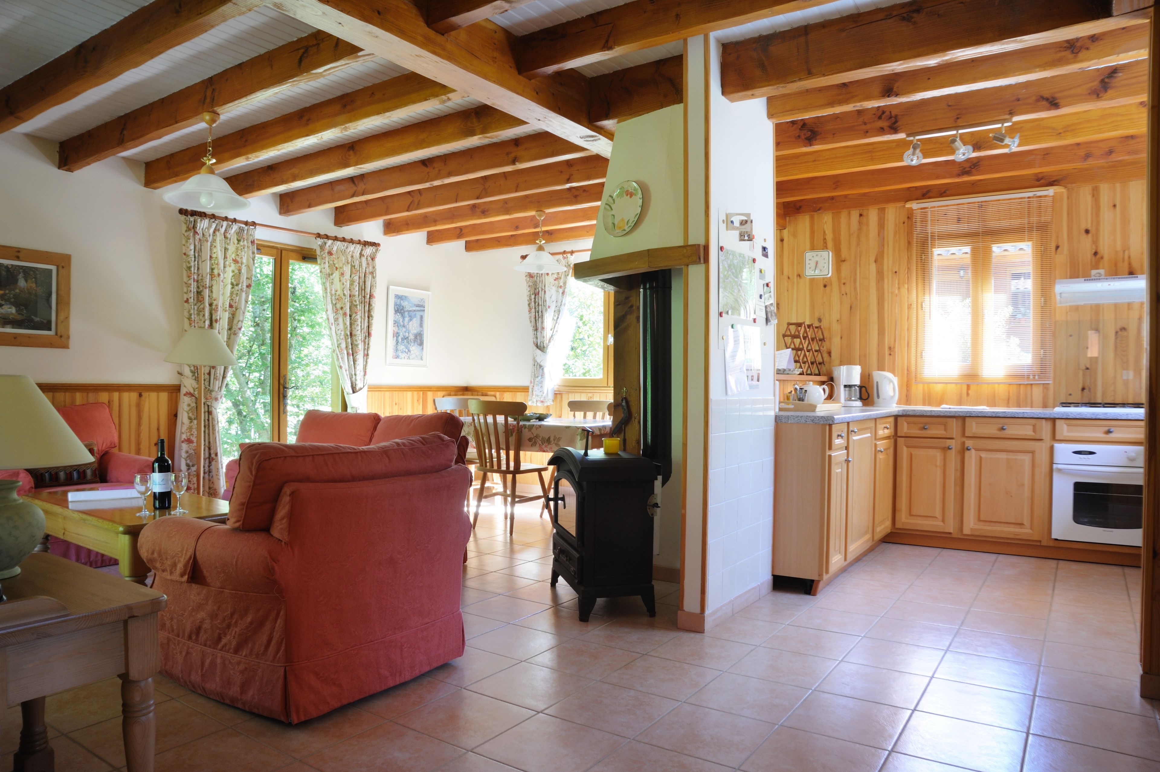 A wooden cabin interior with a dining area, kitchen, and living room.