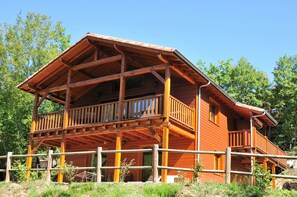 Una cabaña de madera con balcón y patio cercado.