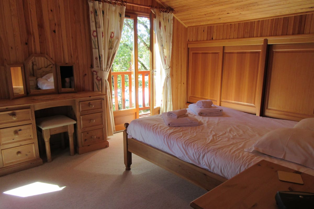 Un dormitorio de cabaña de madera con una cama, un escritorio y una silla pequeña.