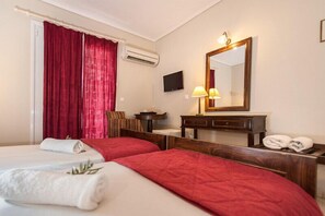 A hotel room with two beds, red curtains, a TV, a lamp, and a mirror. - Alba Hotel (Zakynthos)