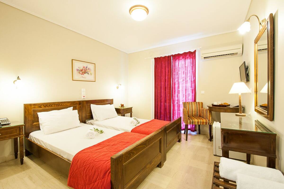 A hotel room with two beds, a chair, a desk, and a mirror.