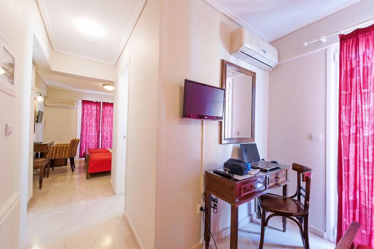 A hotel room with a desk, chair, TV, and a bed.