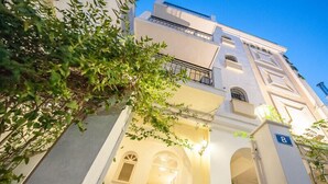 Un edifici de diverses plantes amb façana blanca, portals d'arc i un balcó.