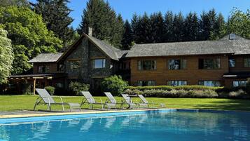 Een buitenzwembad, ligstoelen bij het zwembad