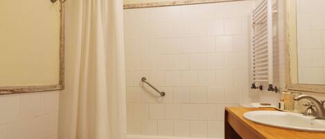 Une salle de bain avec une baignoire, un lavabo et un rideau de douche.