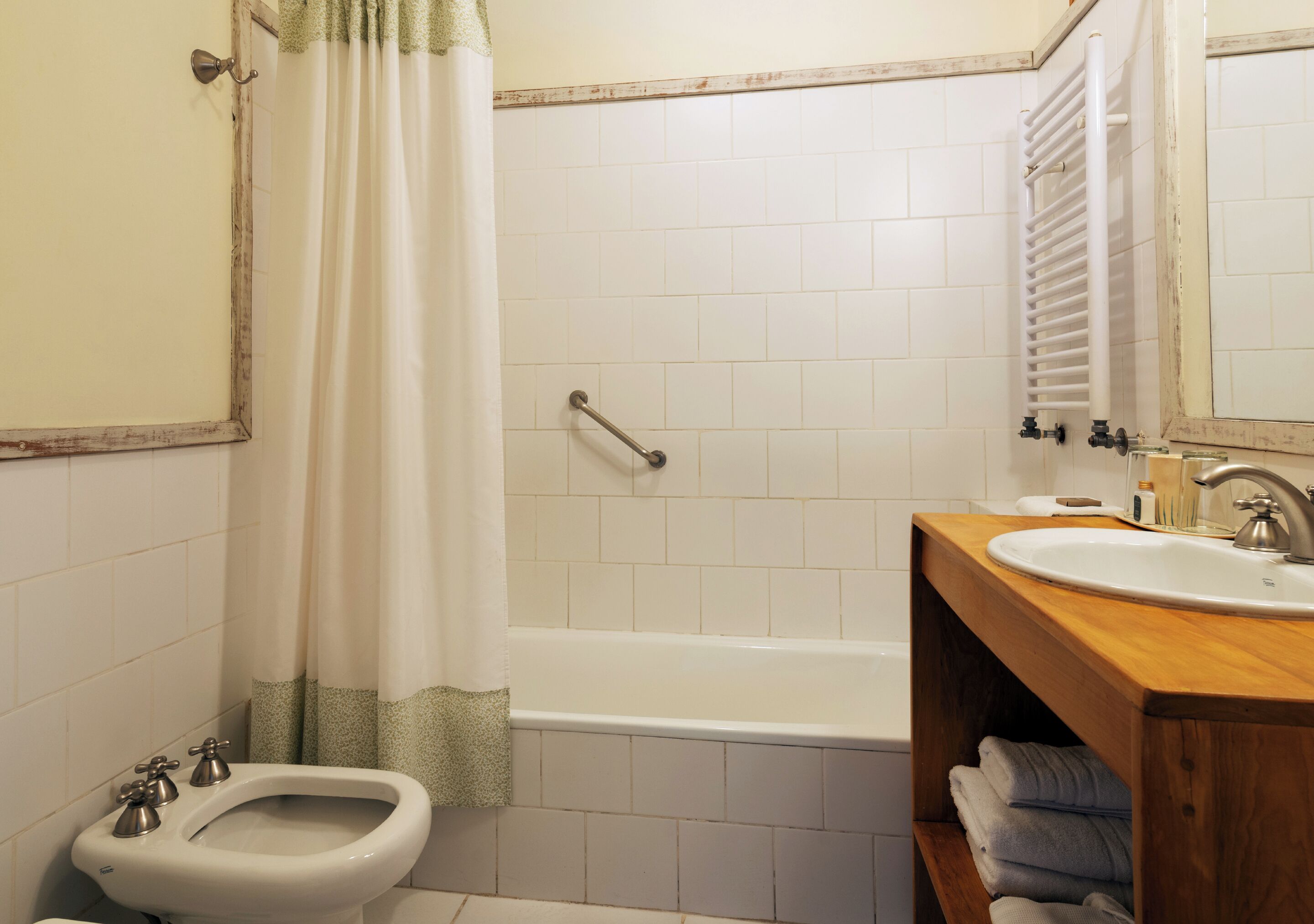 A bathroom with a bathtub, a bidet, a sink, and a wooden vanity.