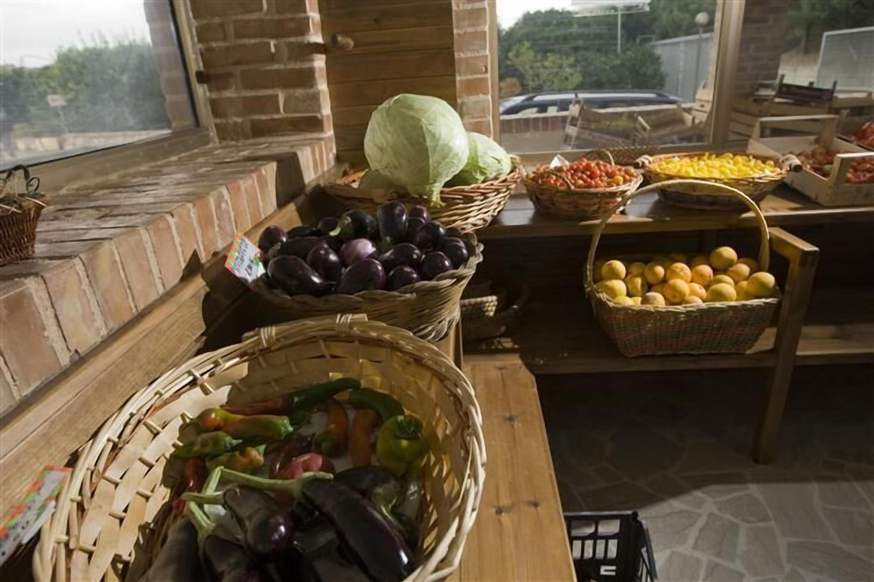 Une cuisine rustique avec un mur en briques, des étagères en bois et des paniers remplis de produits frais.
