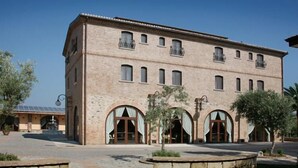 Um edifício grande, com vários andares, fachada simétrica, janelas em arco e varandas.