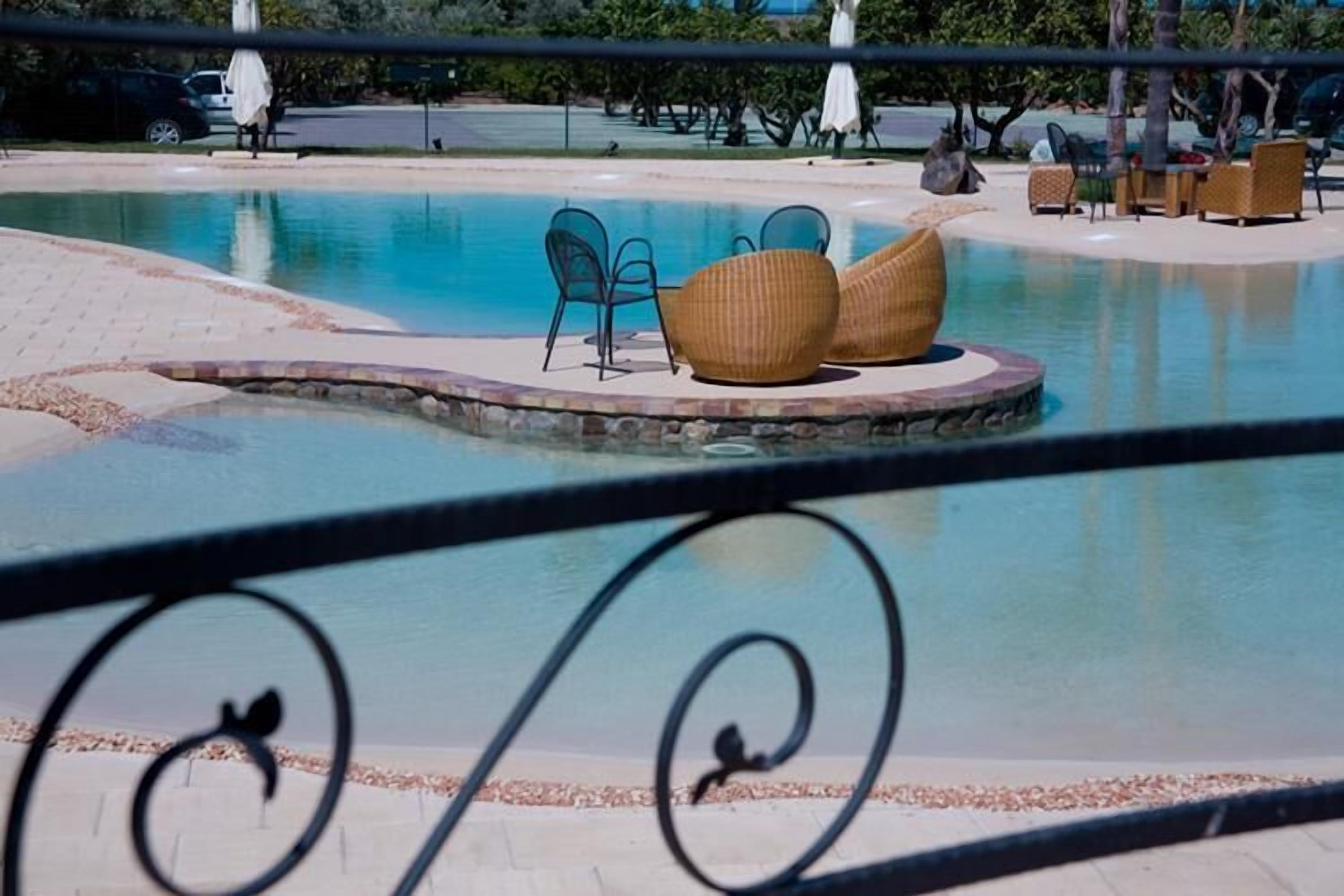 A pool area with lounge chairs and umbrellas.