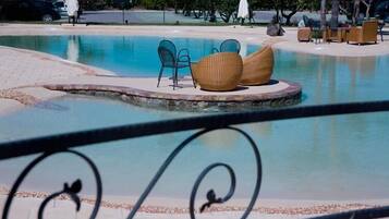 A pool area with lounge chairs and umbrellas.