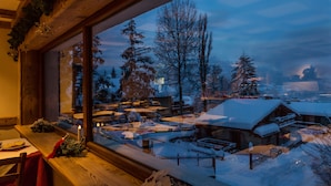 A cozy room with a large window overlooking a snowy village. - Hotel Sauze (Sauze d'Oulx)