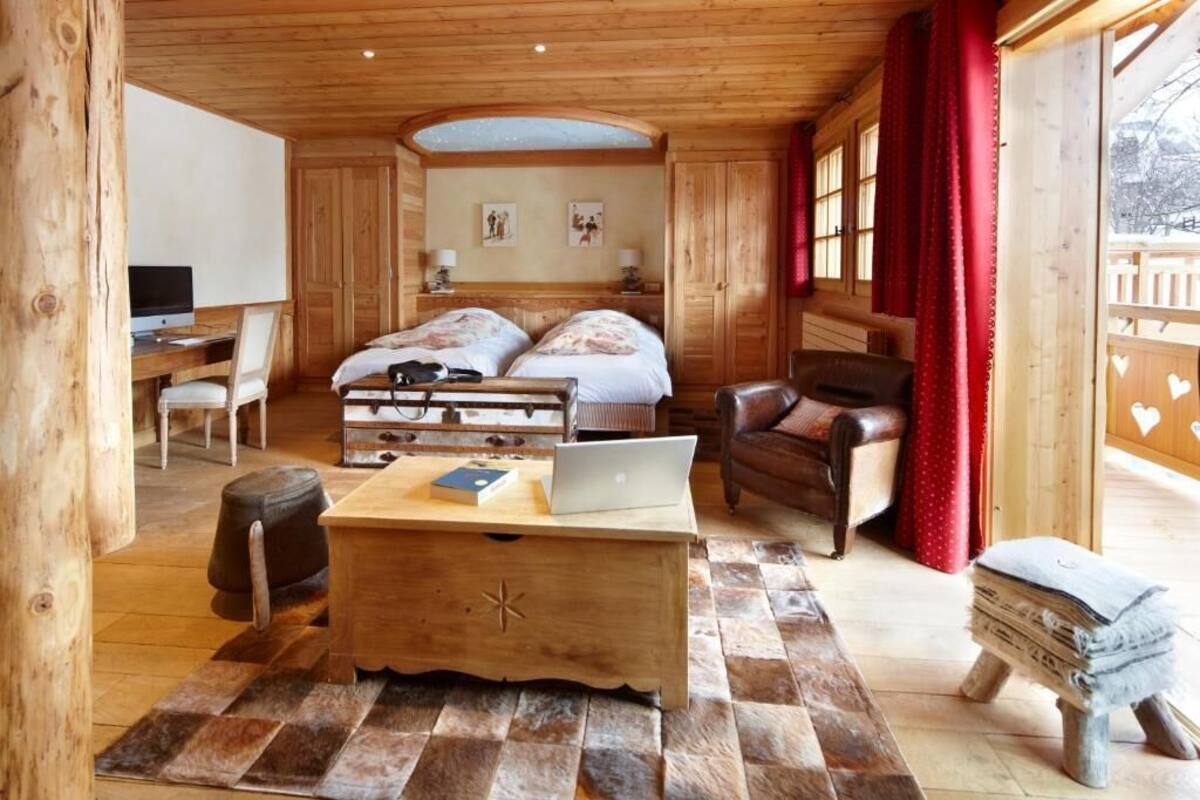 Una habitación acogedora de madera con una cama, un escritorio con una computadora portátil, una silla y una mesita.