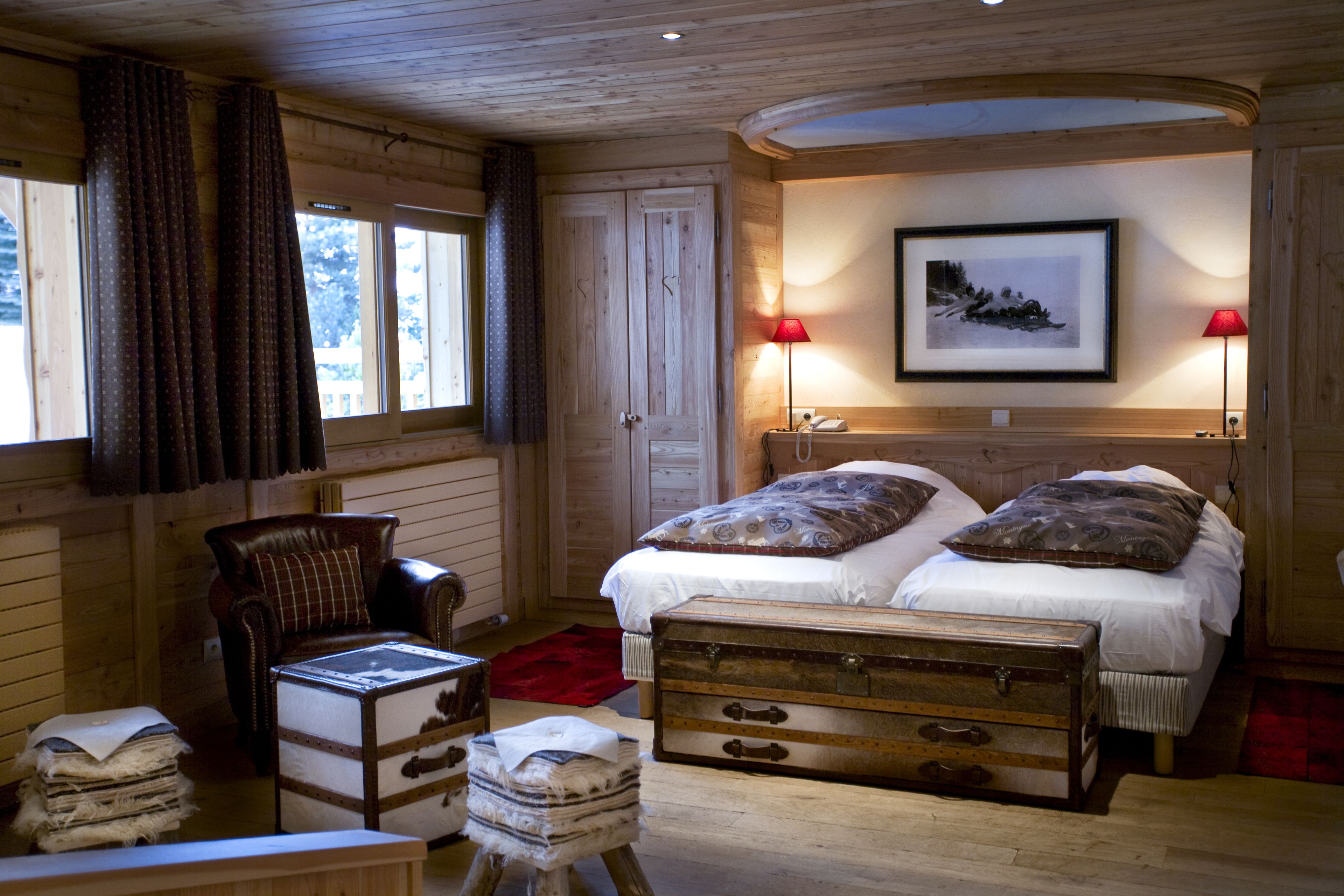 A cozy bedroom with a wooden bed, two bedside lamps, a framed picture on the wall, and a chest of drawers.