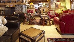 Un interior acogedor y rústico con sofás de cuero, una chimenea de piedra y muebles de madera.