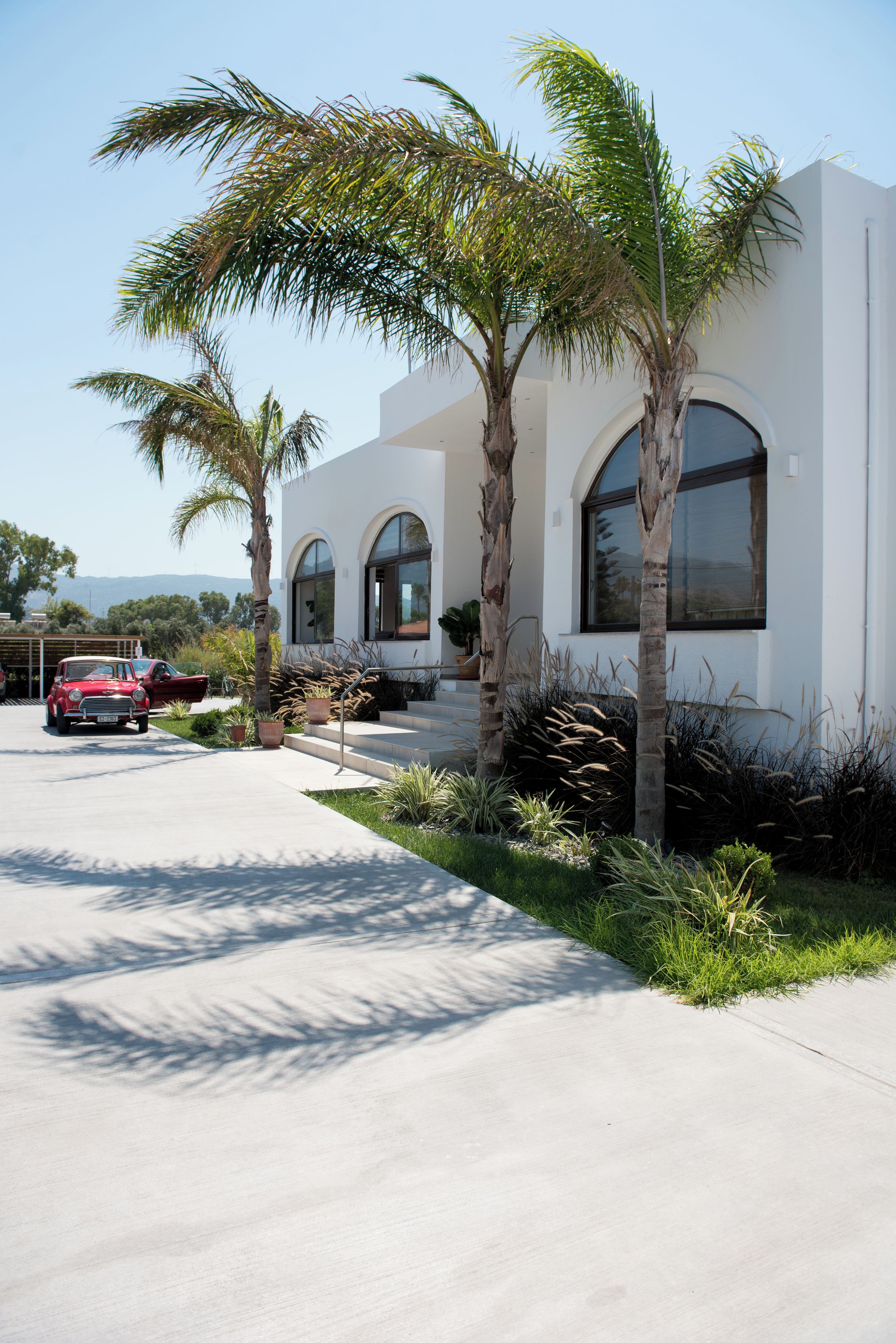 A modern building with arched windows and a concrete driveway.