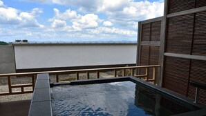 Una piscina en la azotea con vistas al horizonte de la ciudad, rodeada por una valla de madera y un muro de piedra.