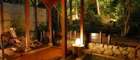 A covered outdoor area with a stone wall, a small pool, and wooden lounge chairs.