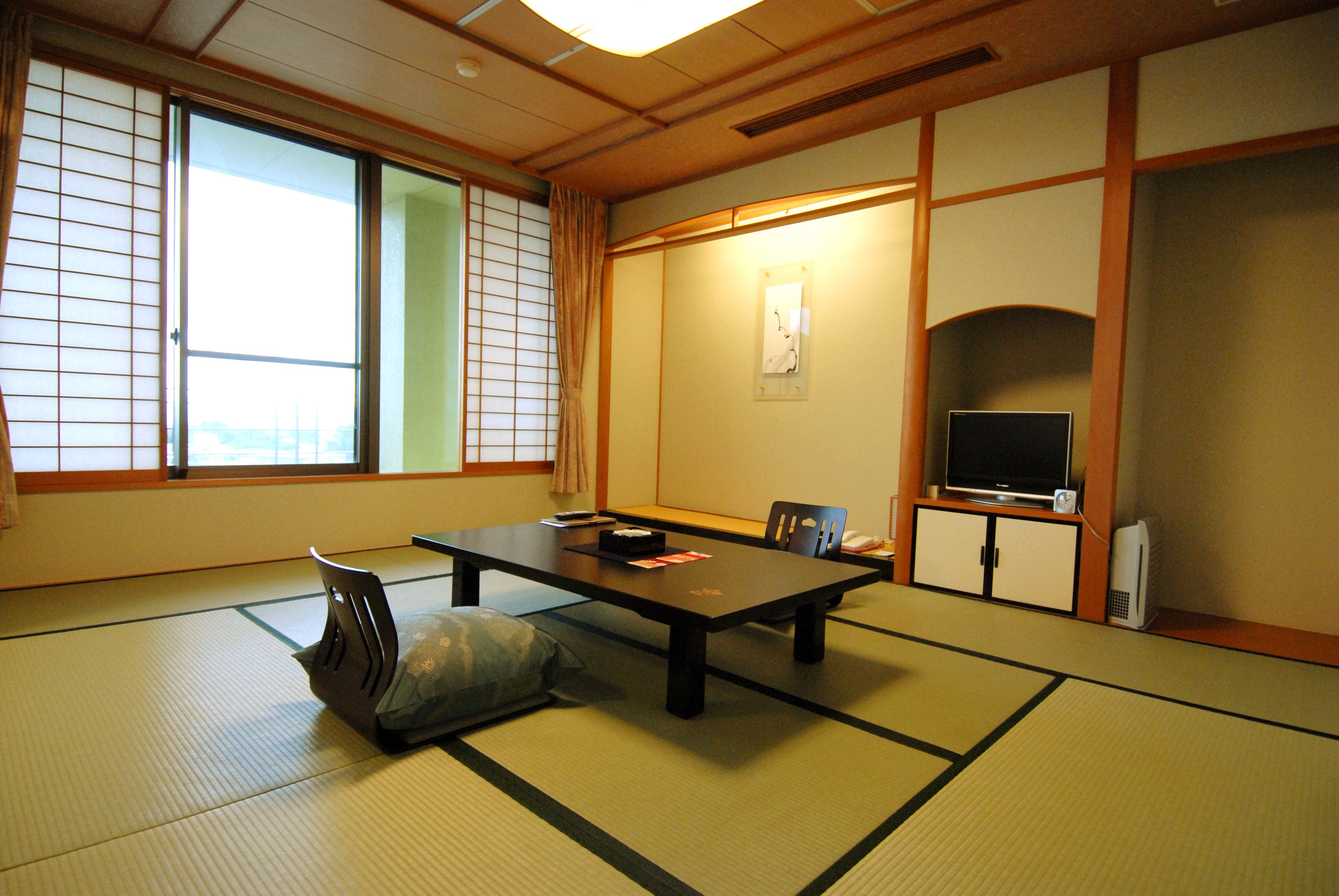 A traditional Japanese room with tatami flooring, a low table, a television, and sliding doors.