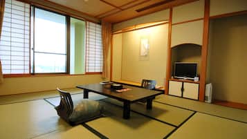 A traditional Japanese room with tatami flooring, a low table, a television, and sliding doors.