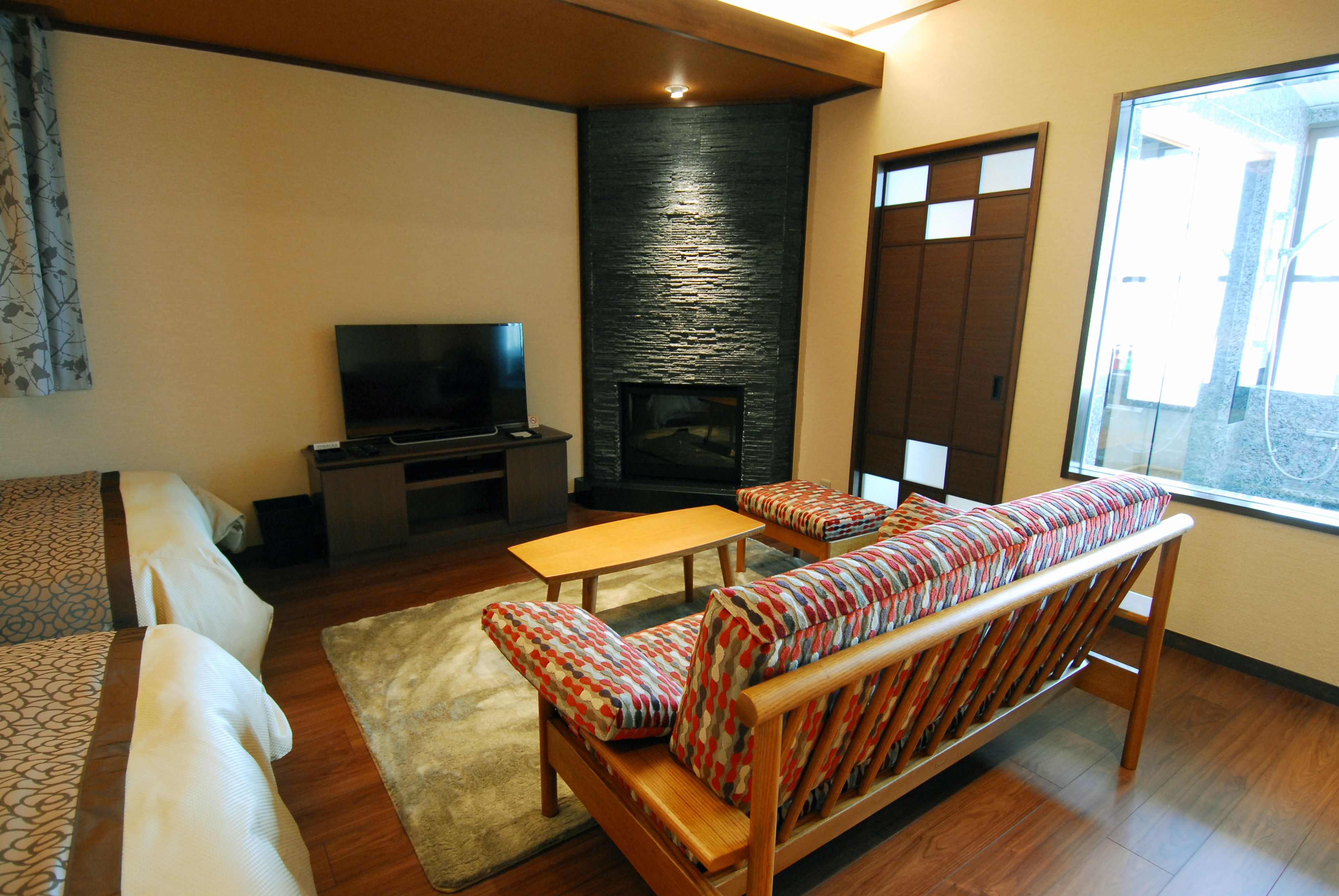 A living room with a sofa, a television, a fireplace, and a window.