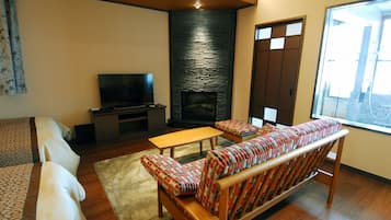 Una sala de estar con sofá, televisión, chimenea y ventana.