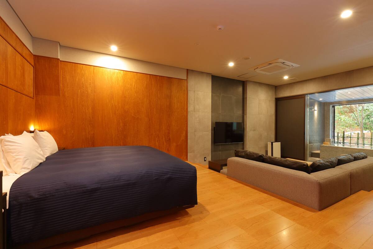 Un dormitorio moderno con una cama grande, un sofá y un televisor.