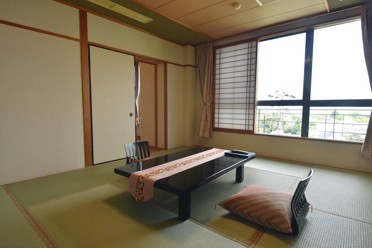 Una habitación con tatami, una mesa baja, un cojín y una puerta corredera.