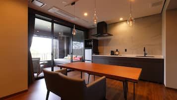 A modern kitchen with a wooden dining table and chairs, a built-in oven, and a large window overlooking a balcony.