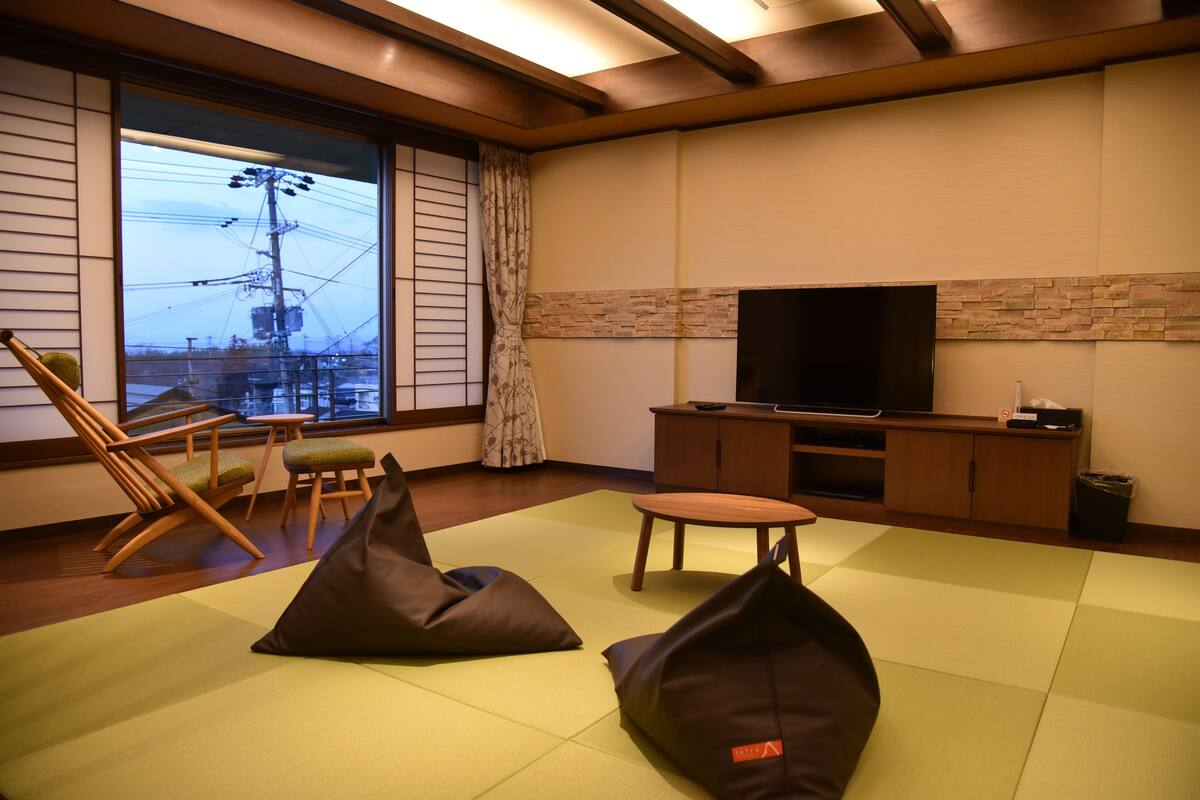 Una sala moderna con esteras de tatami, un televisor y muebles de madera.