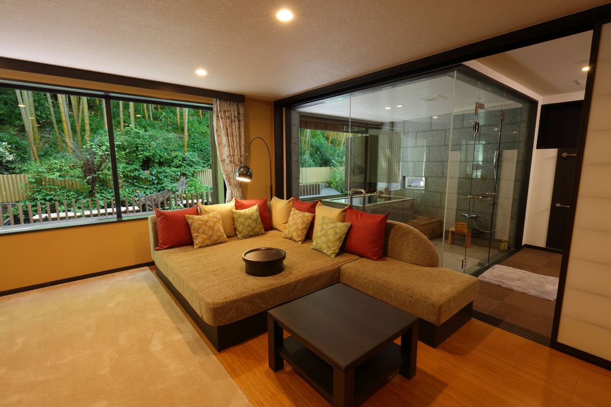 Una sala de estar moderna con un sofá modular, una mesa de centro y un área de ducha con mampara de vidrio visible.