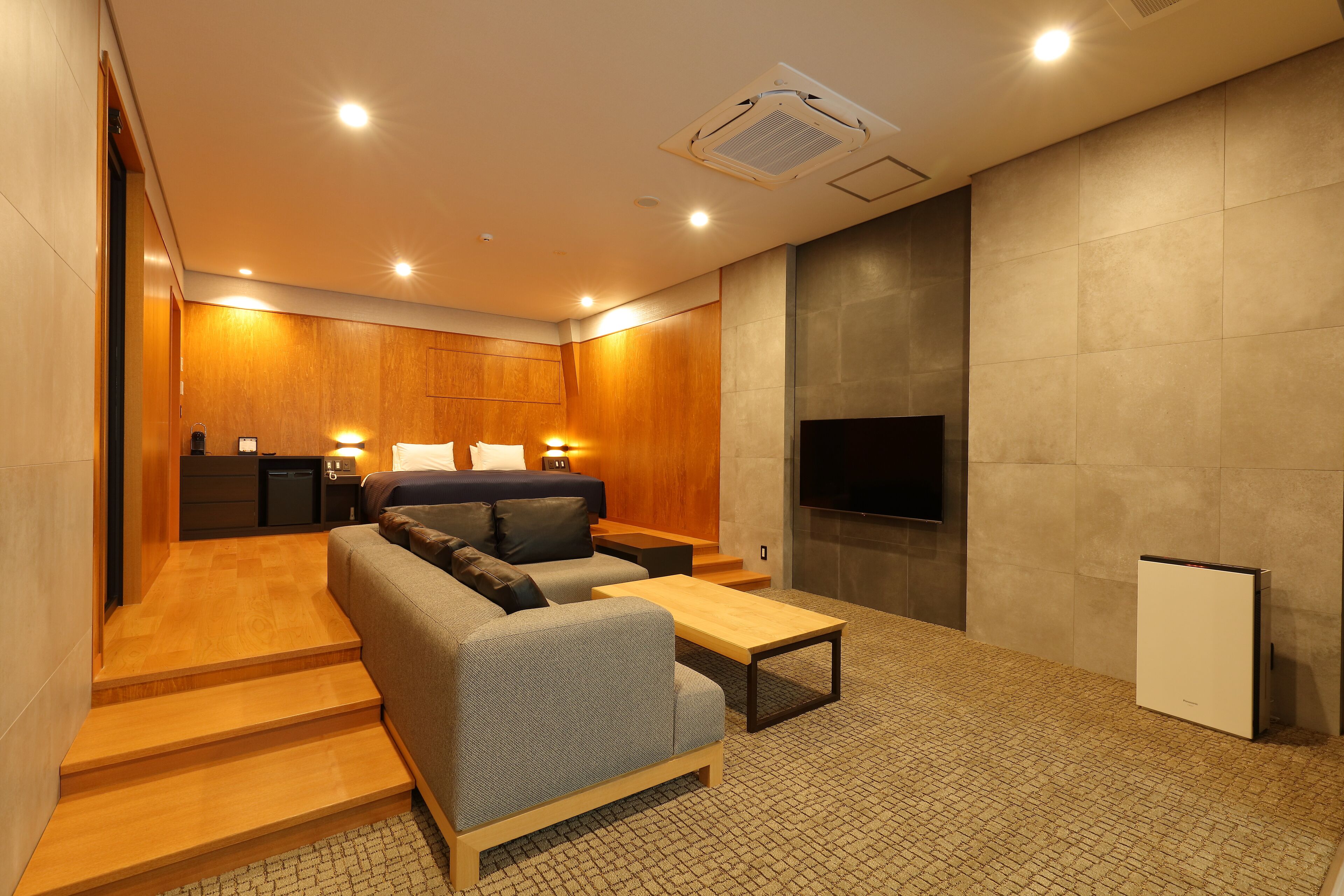 A modern living room with a sofa, coffee table, and a flat-screen TV mounted on the wall.