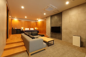 A modern living room with a sofa, coffee table, and a flat-screen TV mounted on the wall.