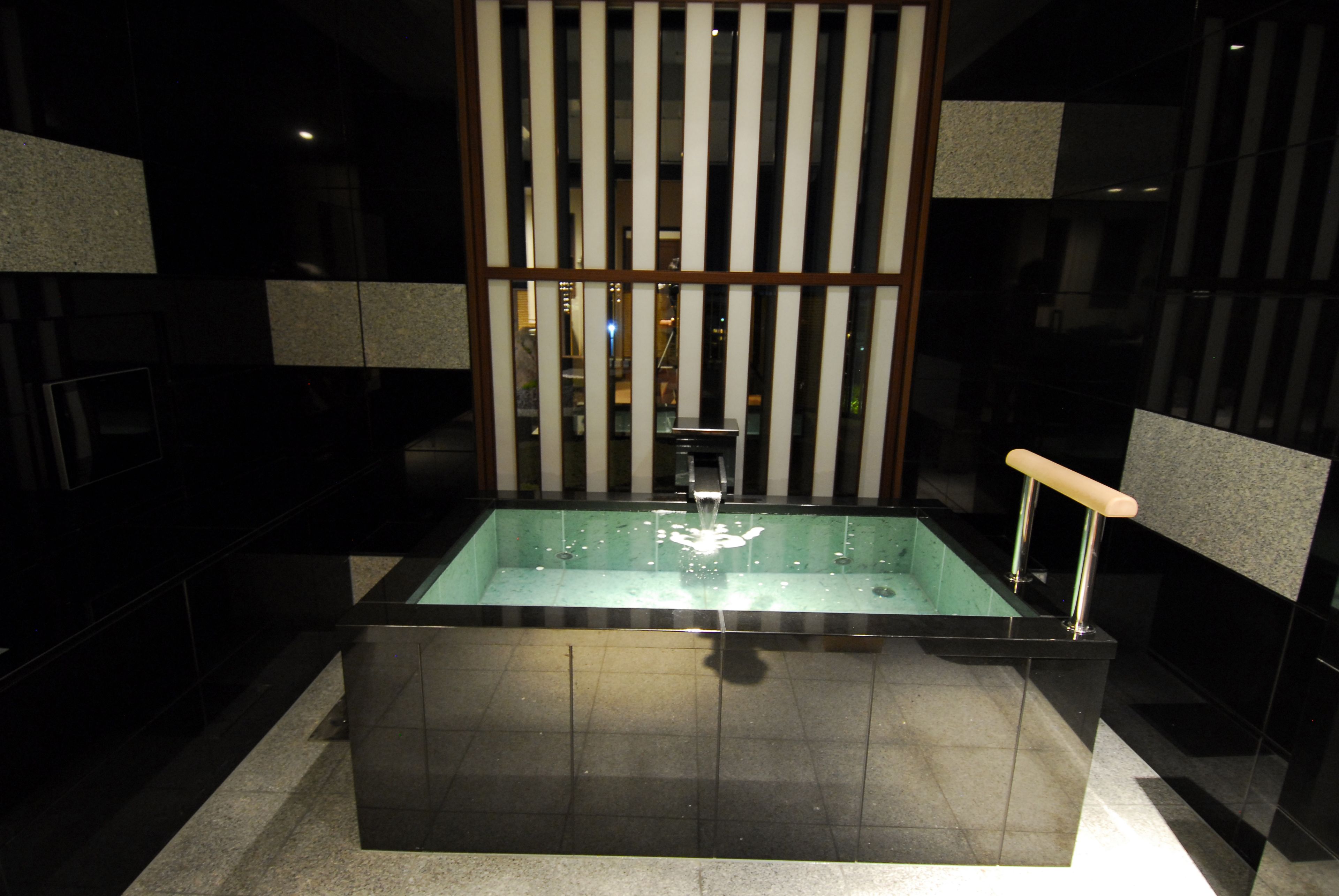 A modern bathroom with a rectangular bathtub, a glass partition, and a wooden panel design.