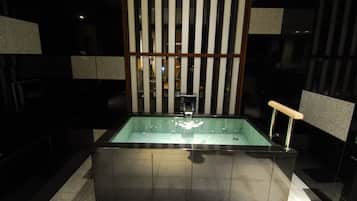 A modern bathroom with a rectangular bathtub, a glass partition, and a wooden panel design.