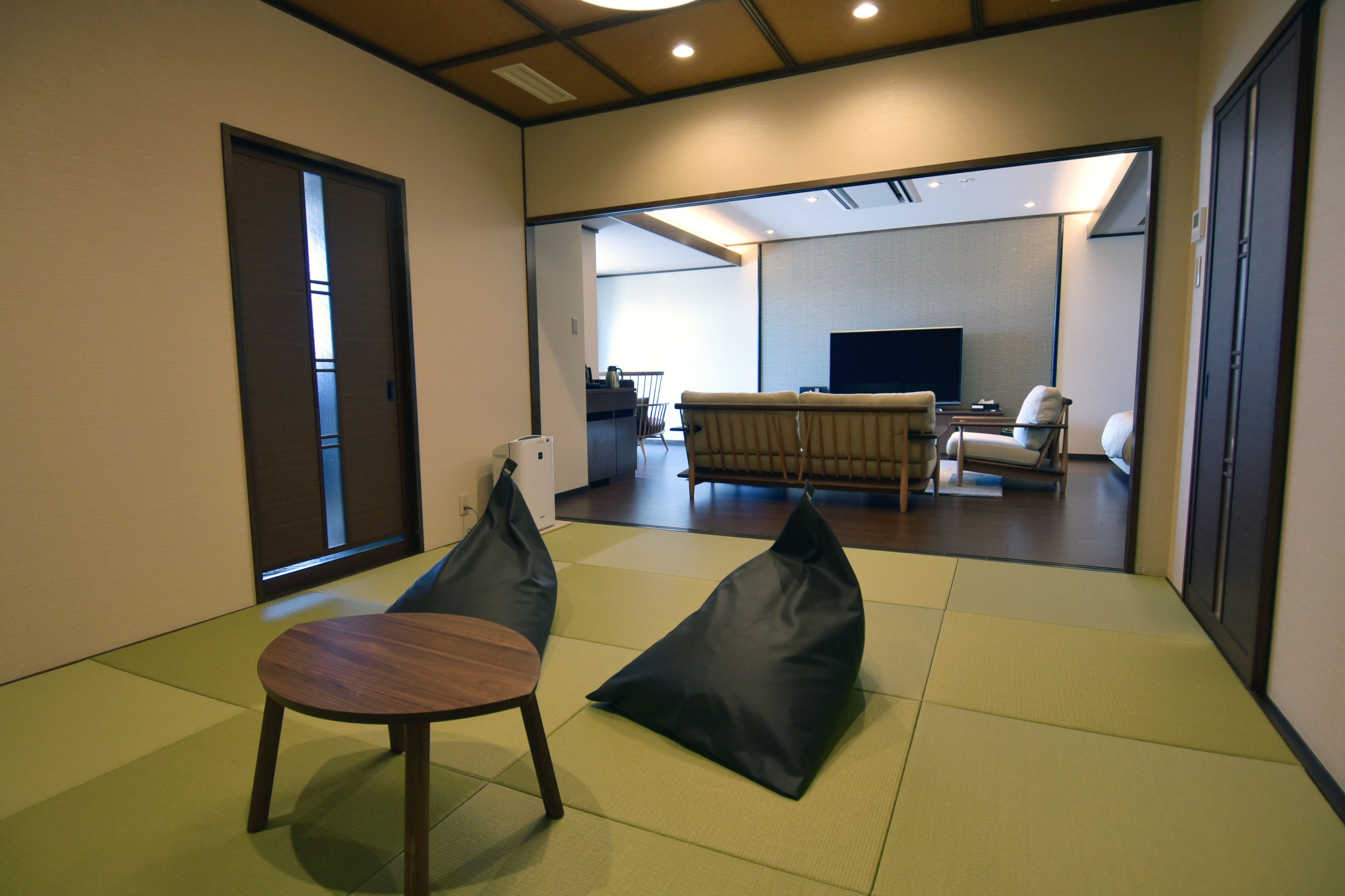 A modern living room with tatami mats, a sofa, a TV, and a dining area.