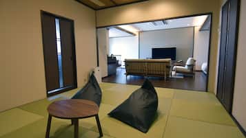 A modern living room with tatami mats, a sofa, a TV, and a dining area.