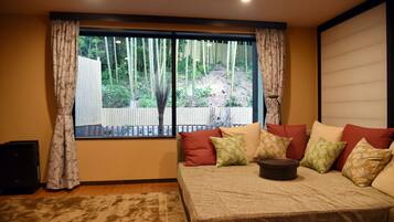 Una habitación con un ventanal grande, un sofá con varios cojines y una mesita.