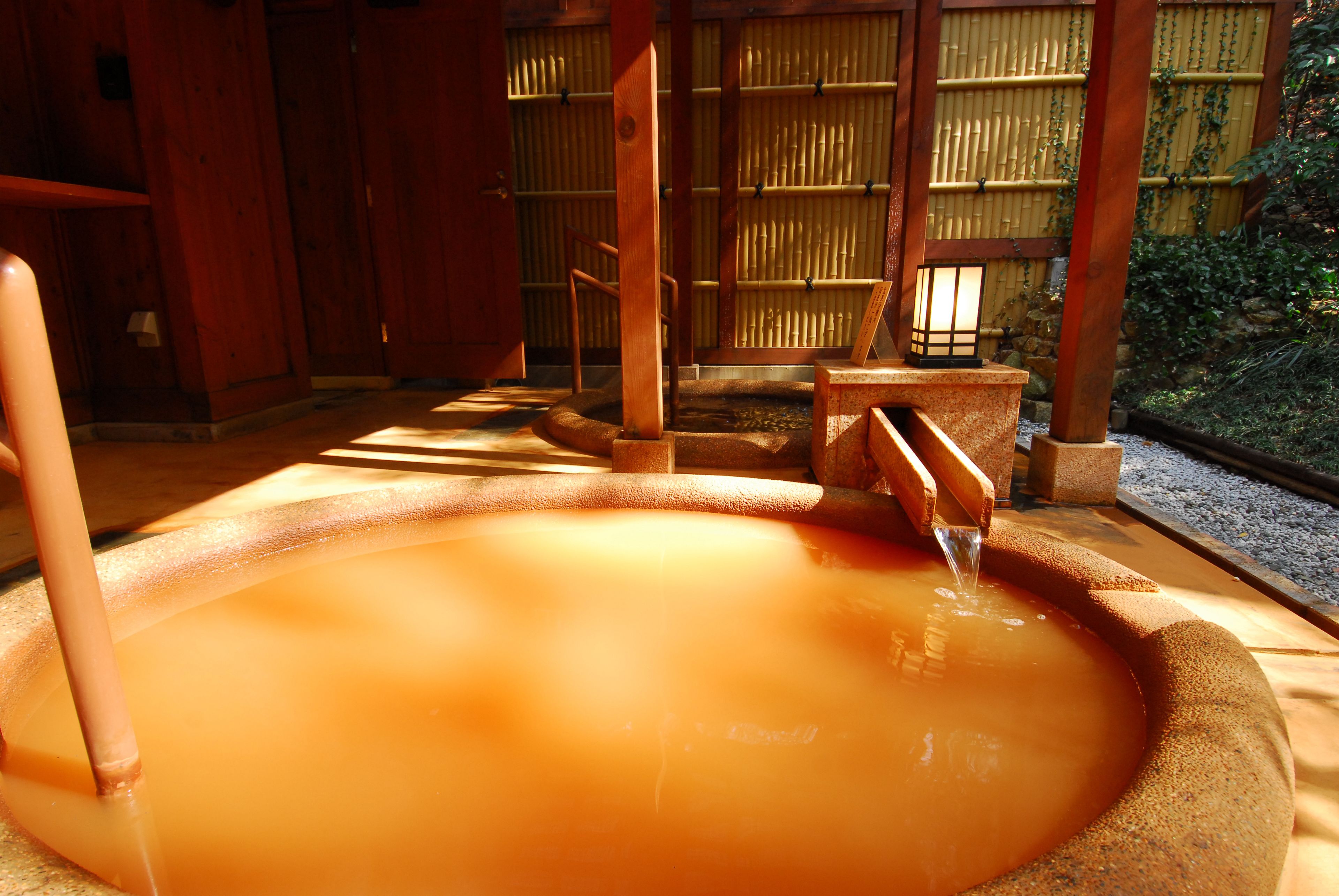 A traditional Japanese onsen with a wooden interior and a stone bath.