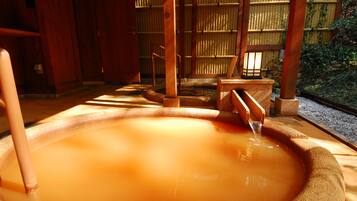 A traditional Japanese onsen with a wooden interior and a stone bath.