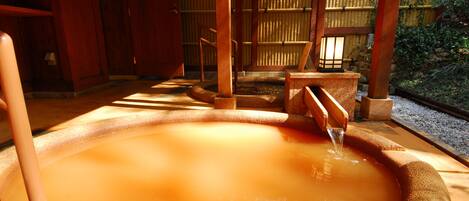 Un onsen japonés tradicional con interior de madera y un baño de piedra.