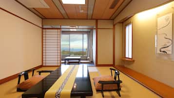 A traditional Japanese room with tatami flooring, a low table with cushions, and a sliding door leading to a balcony.