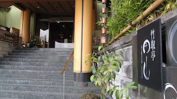 A staircase leading to a building entrance with a signboard and potted plants.