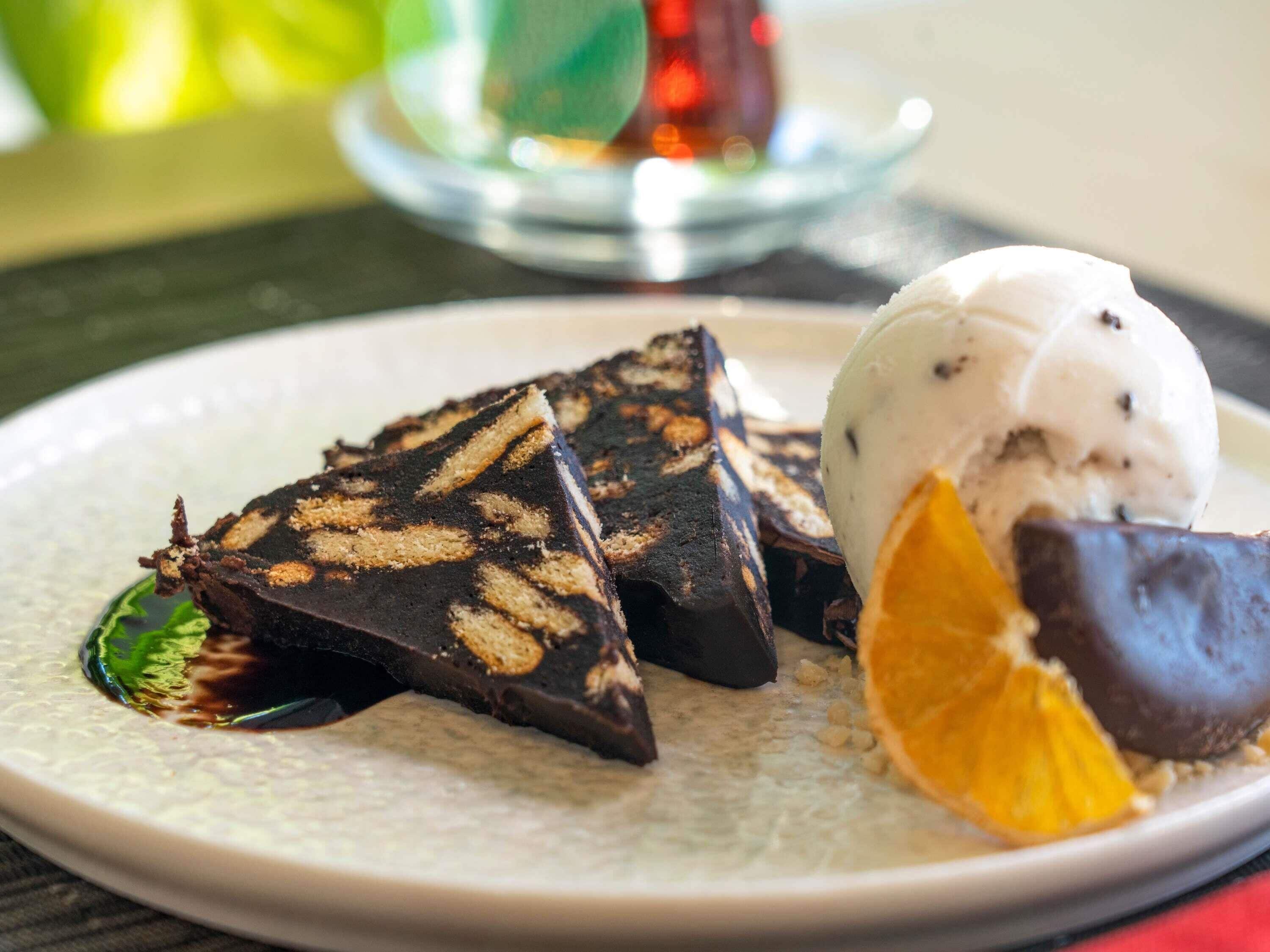 A dessert plate with chocolate pieces and a scoop of ice cream.