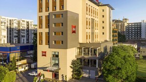 A modern hotel building with multiple floors, a prominent "ibis HOTEL" sign, and a glass entrance. - ibis Adana (Adana)